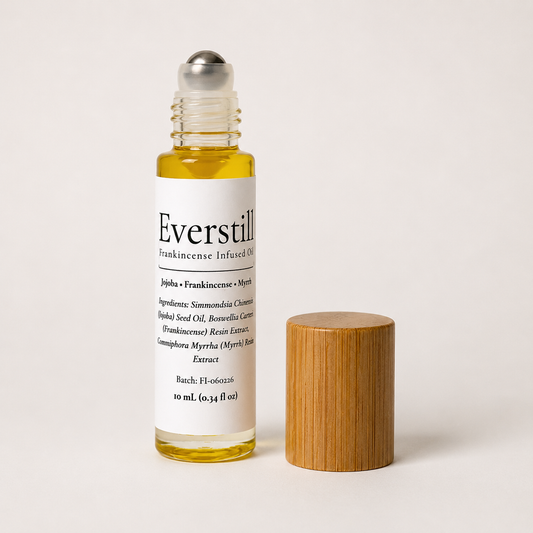 Everstill Frankincense & Myrrh resin-infused jojoba oil roll-on with stainless steel roller ball and bamboo cap beside bottle.