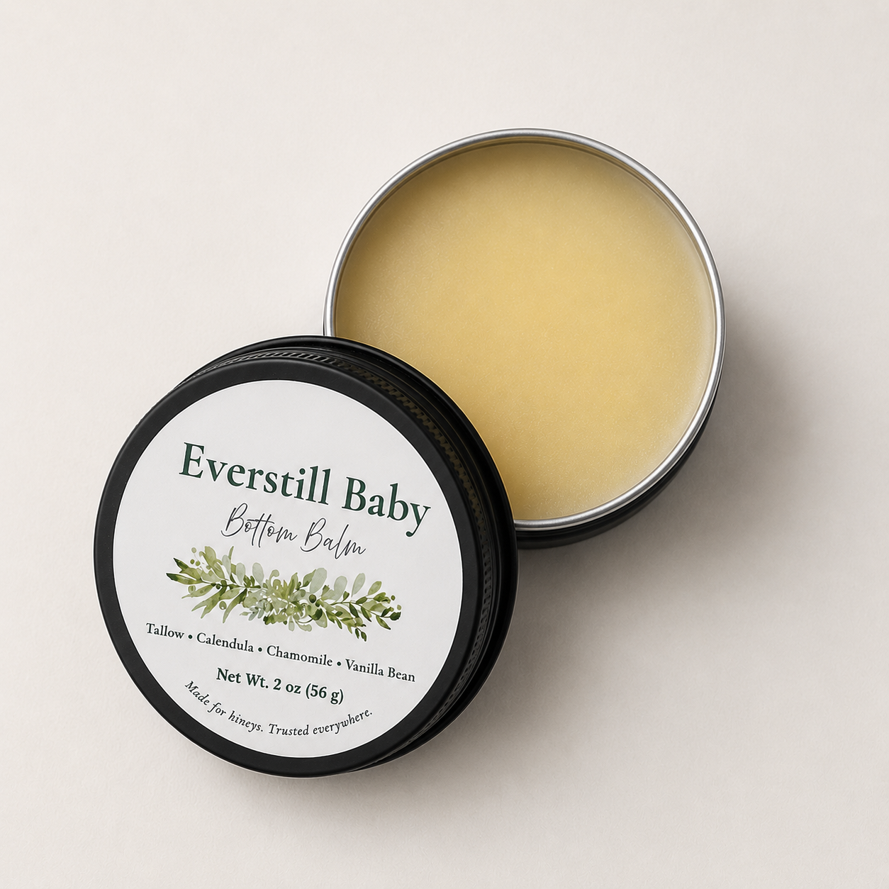 Open tin of Everstill Baby Bottom Balm showing smooth tallow balm beside black labeled lid
